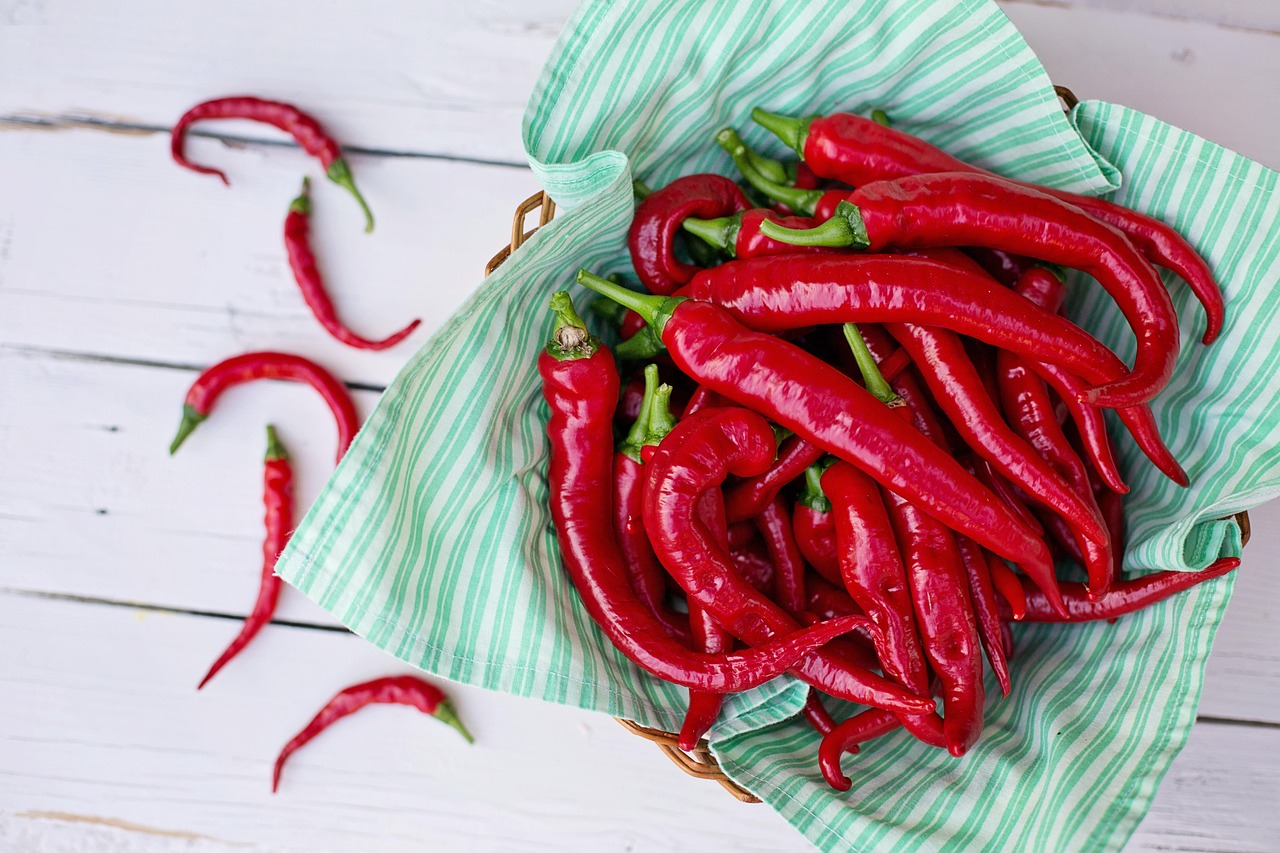 Peperoncino rosso fresco su sfondo bianco, simbolo di benefici e controindicazioni per la salute.