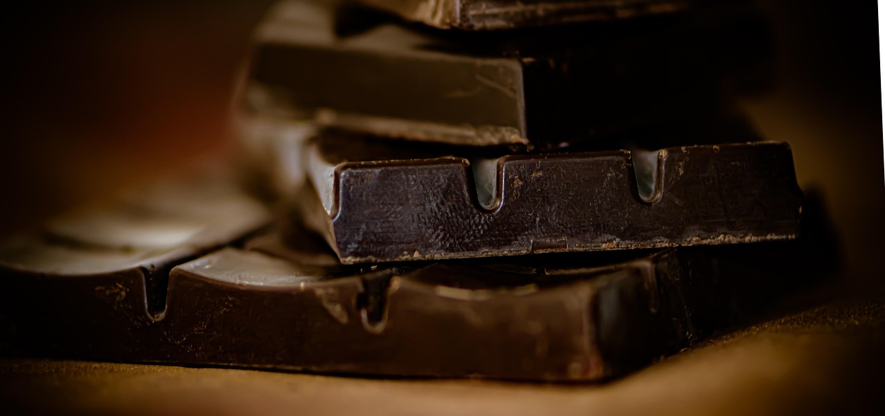 Barretta di cioccolato fondente oltre l'85% su sfondo naturale, simbolo di salute e benessere cardiaco.