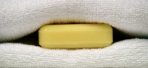 Saponetta posata su lenzuola bianche, simbolo di freschezza e miglioramento del sonno.