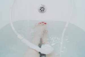 Pediluvio rilassante con sale e aceto per gambe gonfie, immerso in una bacinella d'acqua.